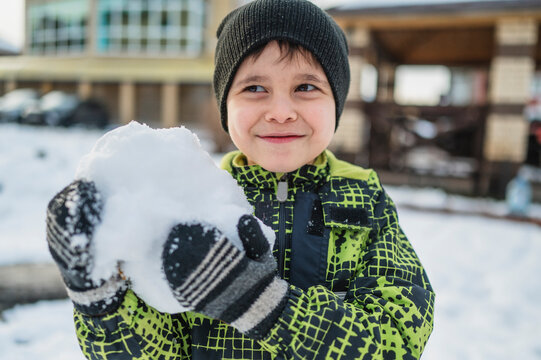 Happy child holding snow and having fun on a winter walk