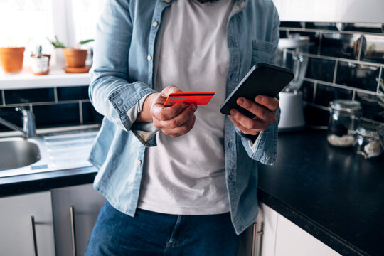 Man with credit card paying bill through smart phone at home