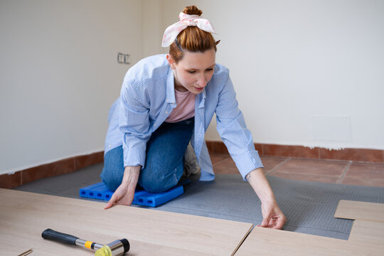 Woman installing laminate flooring during home renovation