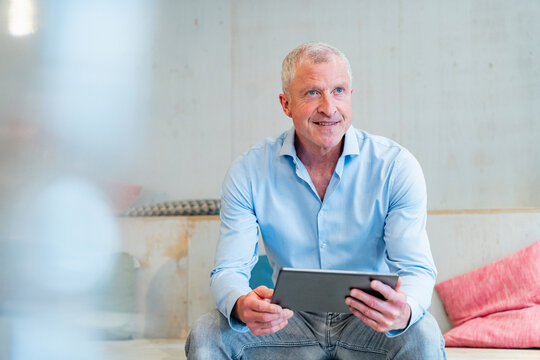 Smiling businessman holding tablet in modern office