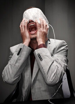 Businessperson screaming with flexible keyboard wrapped around head