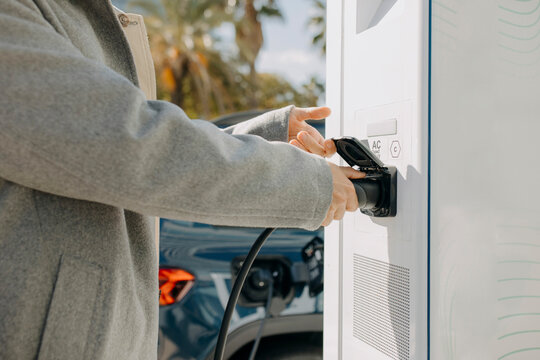 Hand on man plugging car charger at station