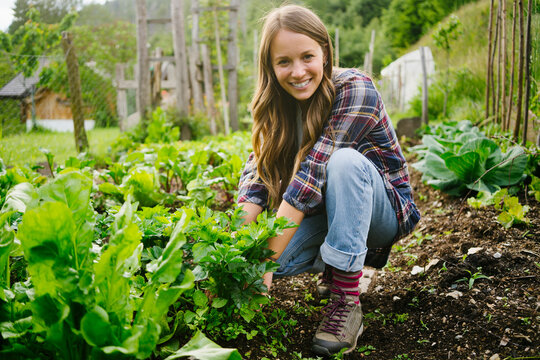 Happy young woman planting vegetables in garden