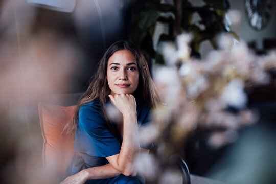 Young businesswoman with hand on chin sitting in office