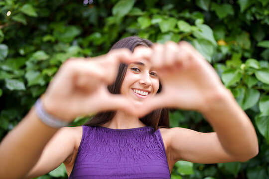 Smiling teenage girl making heart gesture with hands outdoors