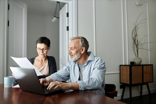 Couple discussing business paper sitting in front of laptop