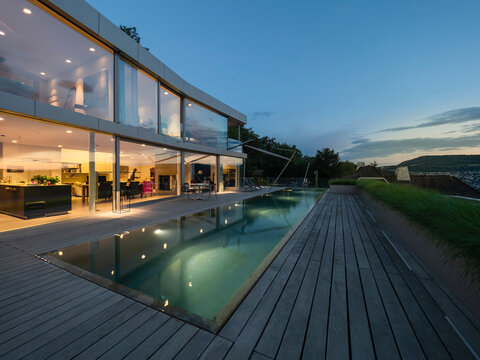Switzerland, lighted modern villa at dusk with terrace and pool in the foreground