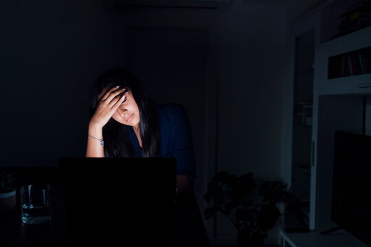 Tired young woman with laptop at home