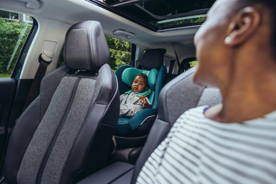 Mother looking at baby boy sitting in car