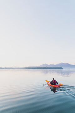 Man paddeling his kayak in the morning on a lake, Germany
