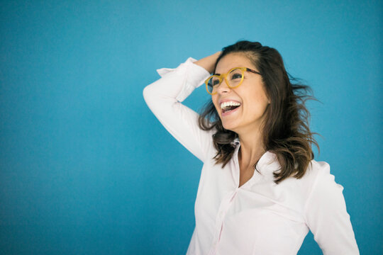 Portrait of laughing woman wearing glasses in front of blue background