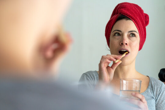 Portrait of woman with head wrapped in a towel brushing heer teeth with wooden toothbrush