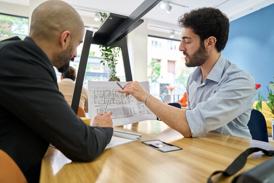 Architects discussing a blueprint at the office desk