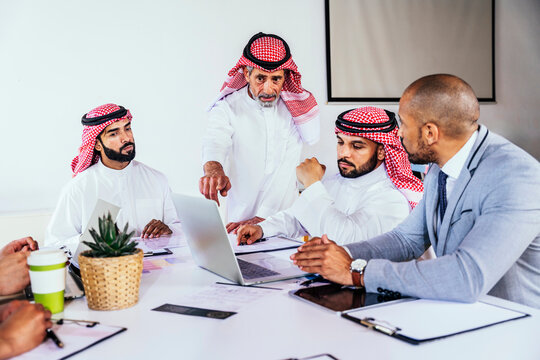 Business team discussing strategy with laptop in Riyadh office