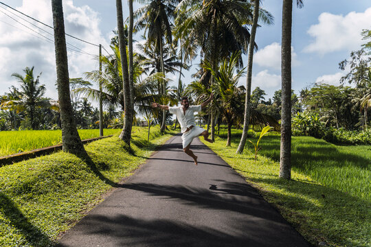 Tourist jumping on a tropical road in Bali Indonesia