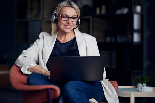 Smiling businesswoman wearing headset working on laptop at office