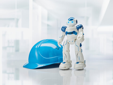 Blue hardhat and toy robot on table in factory