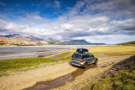SUV on dirt road overlooking vast braided river in Iceland