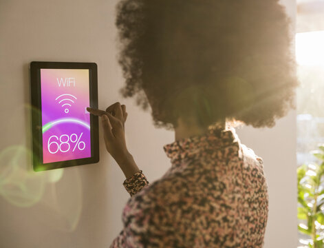 Woman adjusting temperature on smart home touchscreen indoors