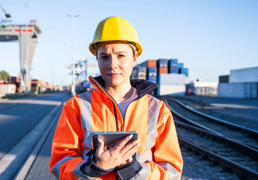 Logistics inspector in safety gear holding tablet at commercial dock