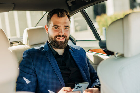 Smiling executive using smartphone in back seat of car