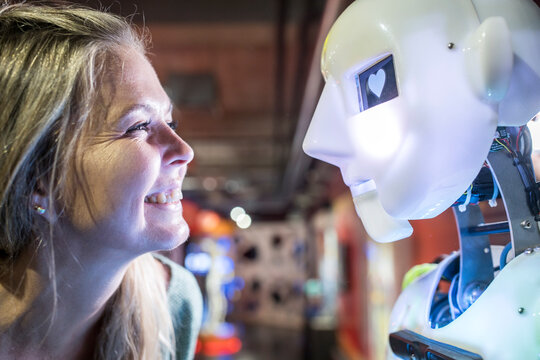 Happy technician looking at human robot with heart shape in eye