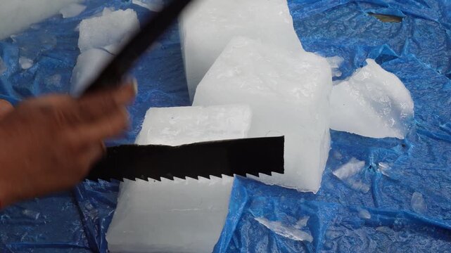 Person Cutting Large Ice Block with Serrated Knife