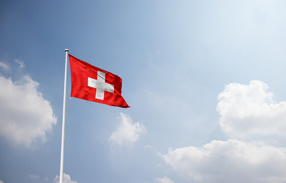 Switzerland flag waving in sky with long mast.