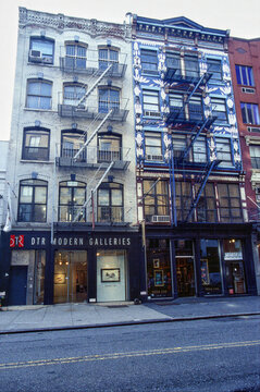 Historic buildings with DTR Modern Galleries and fire escapes on a city street in NYC