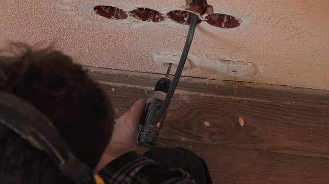 Top view of electrician hands holding a screwdriver before installing a power socket. Preparation for precise electrical installation and home renovation wiring work.