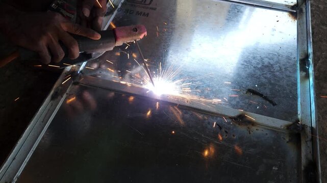Industrial Arc Welding on Steel Metal Frame, Professional Welder Creating Bright Welding Sparks During Metal Fabrication, Manufacturing, Construction, Engineering Workshop