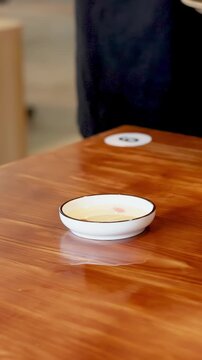 Server Placing Vietnamese Banh Beo Rice Cakes on Wooden Restaurant Table