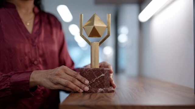 A stunning gold and marble trophy held by a person, showcasing intricate geometric designs, symbolizing achievement and recognition in a modern interior setting.