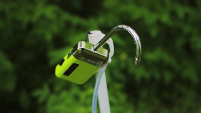 Bright green portable water dispenser detail. Metallic curved spout, white tubing visible. Product for outdoor recreation, convenient hydration. Blurred green foliage background shows readiness.