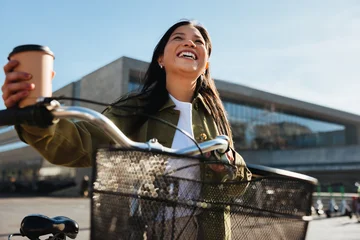 Woman with bicycle holding coffee, smiling on commute © Jacob Lund