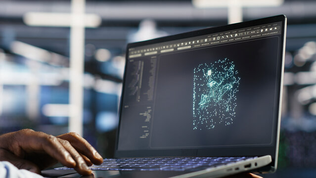 System administrator uses a laptop to manage AI training datasets and database workflows inside a server room.
