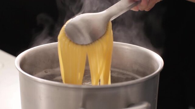 黒バックで茹でたパスタをトングであげる