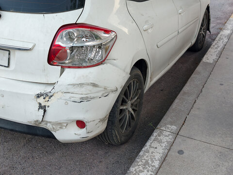 Car with damage parked on the street during daylight in an urban area near buildings