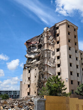 Building demolition takes place under a blue sky with clouds in a city location during the day