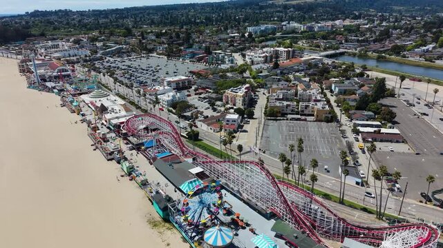 Aerial drone view of the Santa Cruz Beach Boardwalk, featuring the Giant Dipper roller coaster, Ferris wheel, and beach.