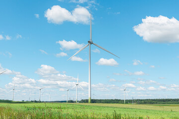 Wind turbines in a scenic agricultural landscape with green fields. Beautiful rural view with wind power generators and a bright blue sky. © ARVD73
