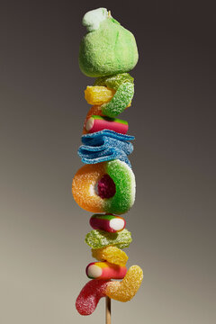 Multicolored sour jelly candy in various shapes stacked on a skewer