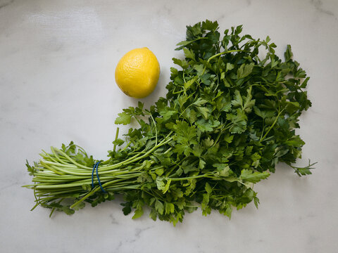Still life of lemon and parsley bunch on white marble surface