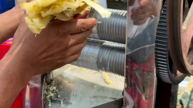 Close-up of extracting fresh juice from sugarcane using an electric roller machine in image