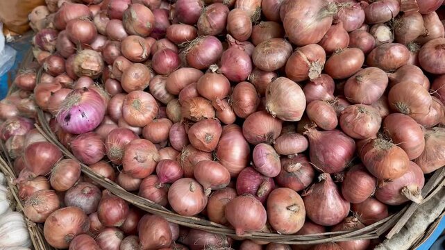 Close up view of a large pile of fresh red onions displayed in a woven basket at a market market stall.