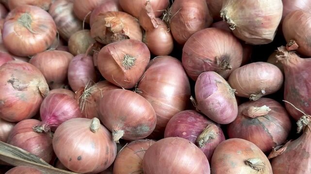 Close up view of a large pile of fresh red onions displayed in a woven basket at a market market stall.