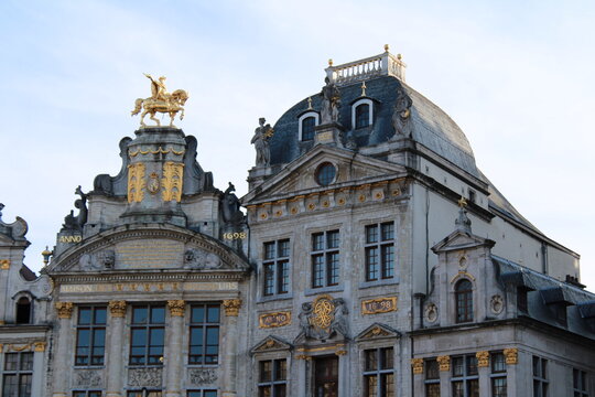 Ornate Baroque guild houses with gilded statues at the Grand Place in Brussels, Belgium, including the golden equestrian statue crowning the historic Brewers' Guild house, in evening light