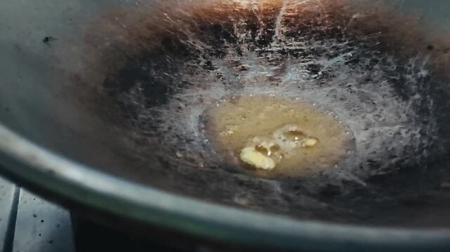 A dirty, old metal bowl with scratches and stains, containing murky water and debris
