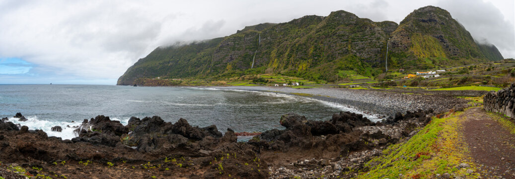 Beach with round stones, framed by waterfalls in Faj&atilde; Grande. Flores Island, Azores, Portugal.