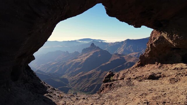 Stunning aerial view flying backwards through the Aserrador Arch, a natural rock formation in Gran Canaria shaped like an elephant and camel